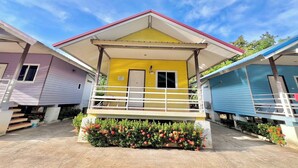 Una hilera de casas móviles de colores, con una unidad amarilla en el centro, cada una con un porche y barandillas.