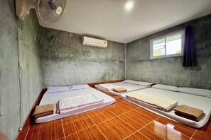 A room with four beds arranged in a row, an air conditioning unit, a ceiling fan, and a window with curtains. - Chalalai Resort Kham Chanot By Zuzu (Ban Dung)