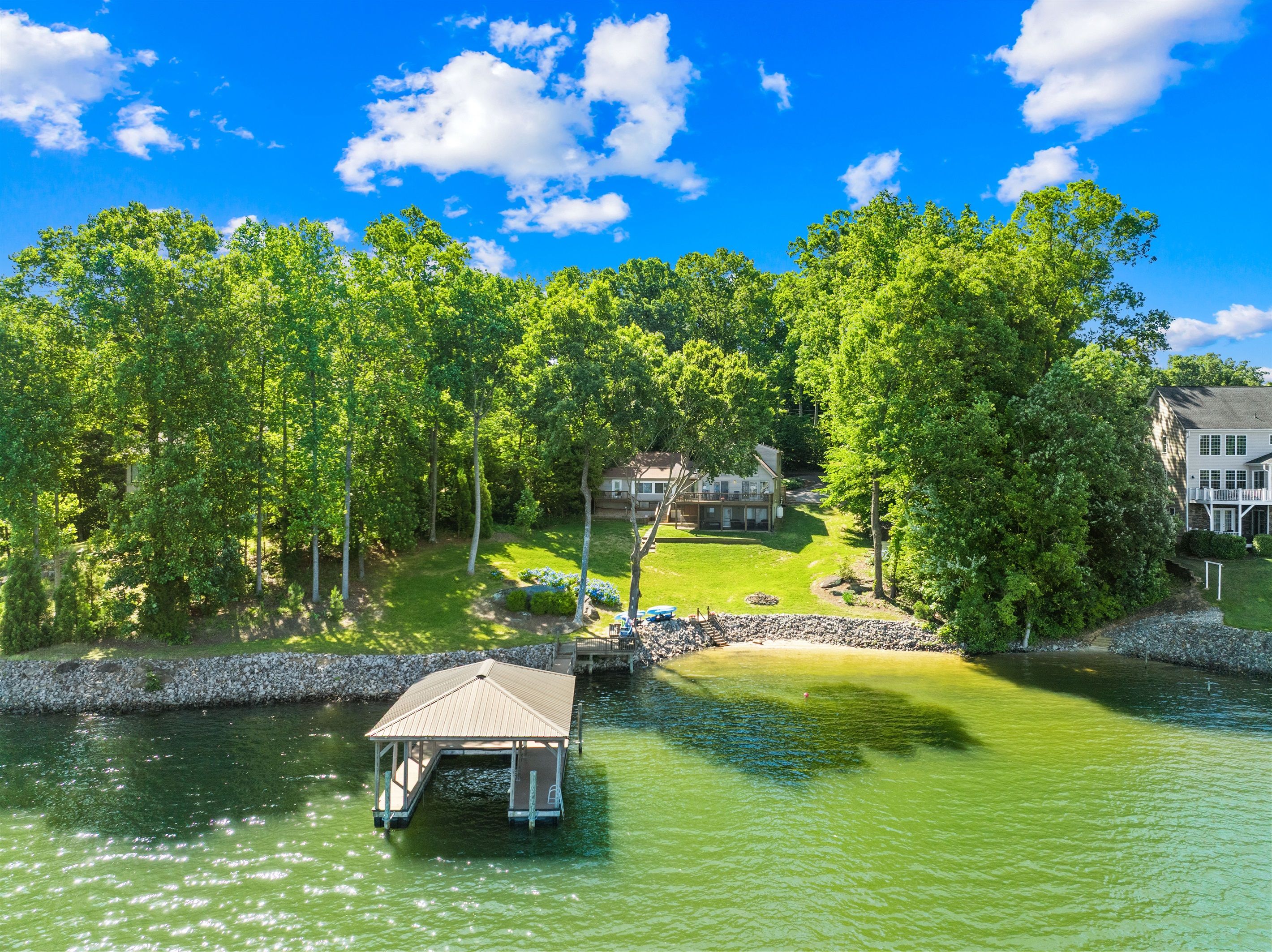 A lakeside property with a dock, a house, and lush greenery.