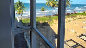 A view from a window overlooking a beach with palm trees and the ocean. - La Playa 204 Vista Livre ao Mar by LP (Ipojuca)