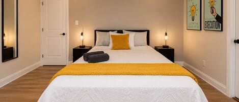 A bedroom with a bed, two bedside tables, a door, and two wall art pieces.