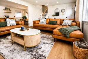Una sala de estar moderna con sofás de cuero, una mesa de centro y una escalera.