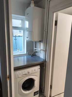 A compact laundry area with a washing machine, a dryer, and a water heater.