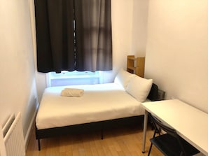 A small, single-bed room with a window, a bedside table, and a radiator. - Spacious, comfortable base for exploring london! (Greater London)