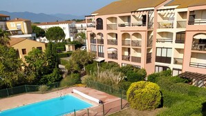 Edificio residencial con piscina, rodeado de vegetación y cielo despejado.