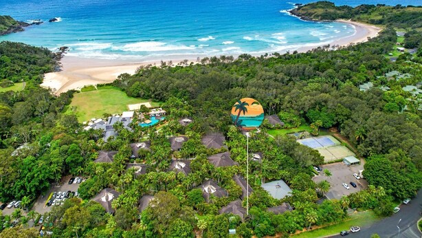 Vista aérea de un complejo turístico costero con varios edificios, una playa y un campo de golf.