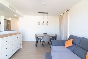 A modern living room with a grey sofa, a wooden dining table, and a white cabinet.
