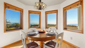 Un coin repas avec une table ronde, quatre chaises et de grandes fenêtres offrant une vue panoramique.