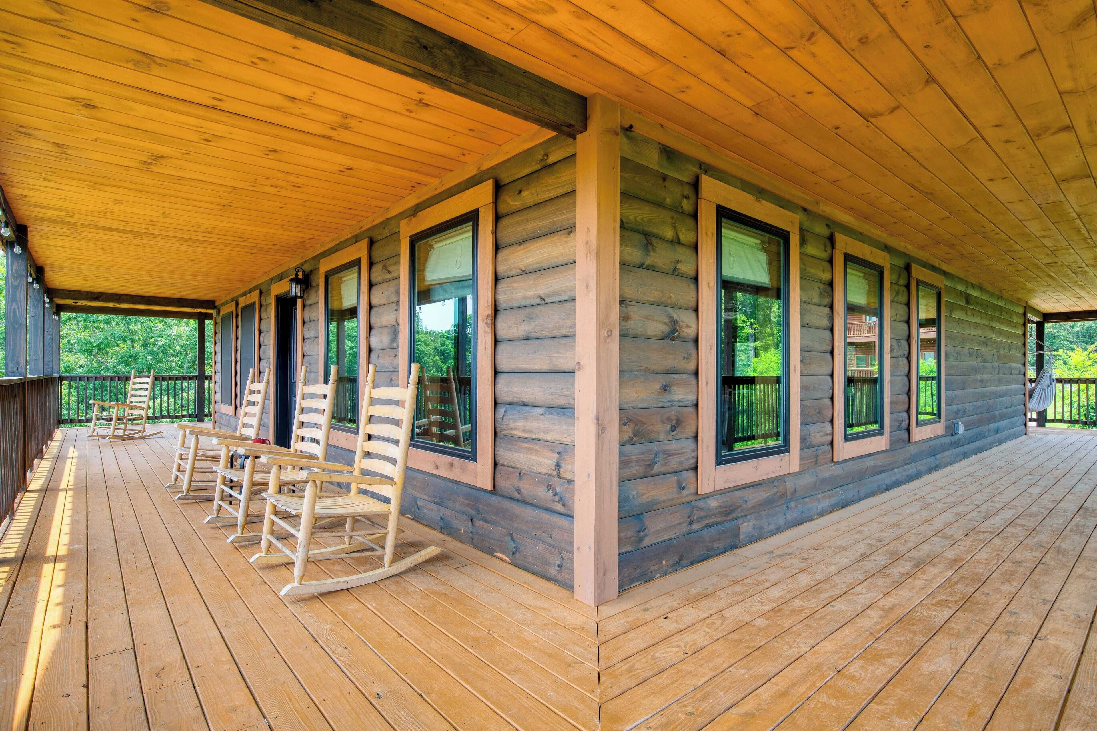 Eine überdachte Holzterrasse mit Schaukelstühlen und großen Fenstern.