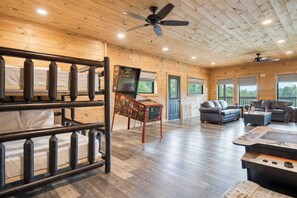 A cabin interior with bunk beds, a gaming table, and a seating area with couches. - Lions Landing by Avantstay Sleeps 12, Hot Tub + Game Room + Views Near Pigeon Forge (Sevierville)