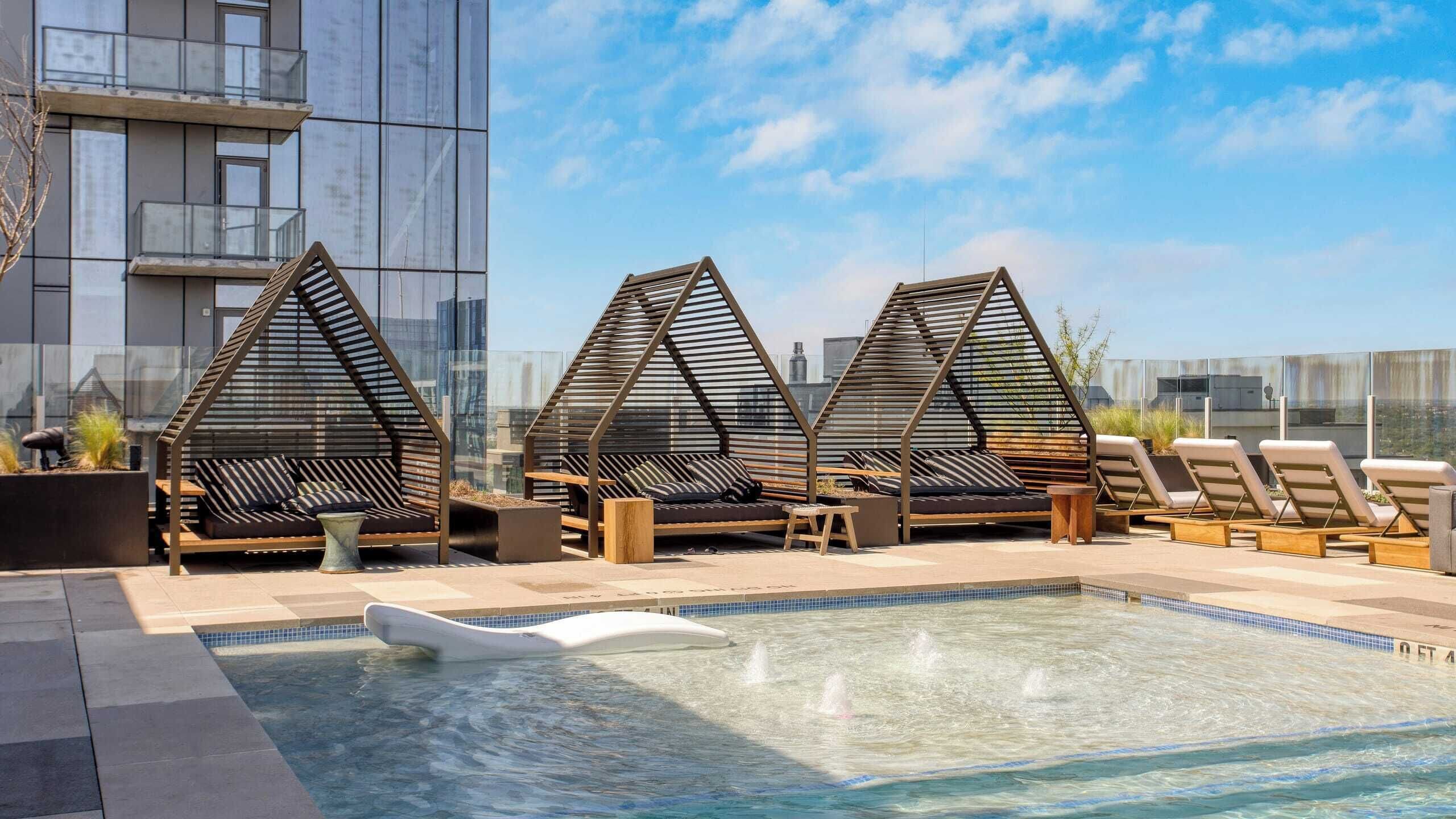 Un área de piscina en la azotea con sillones de descanso y una piscina.