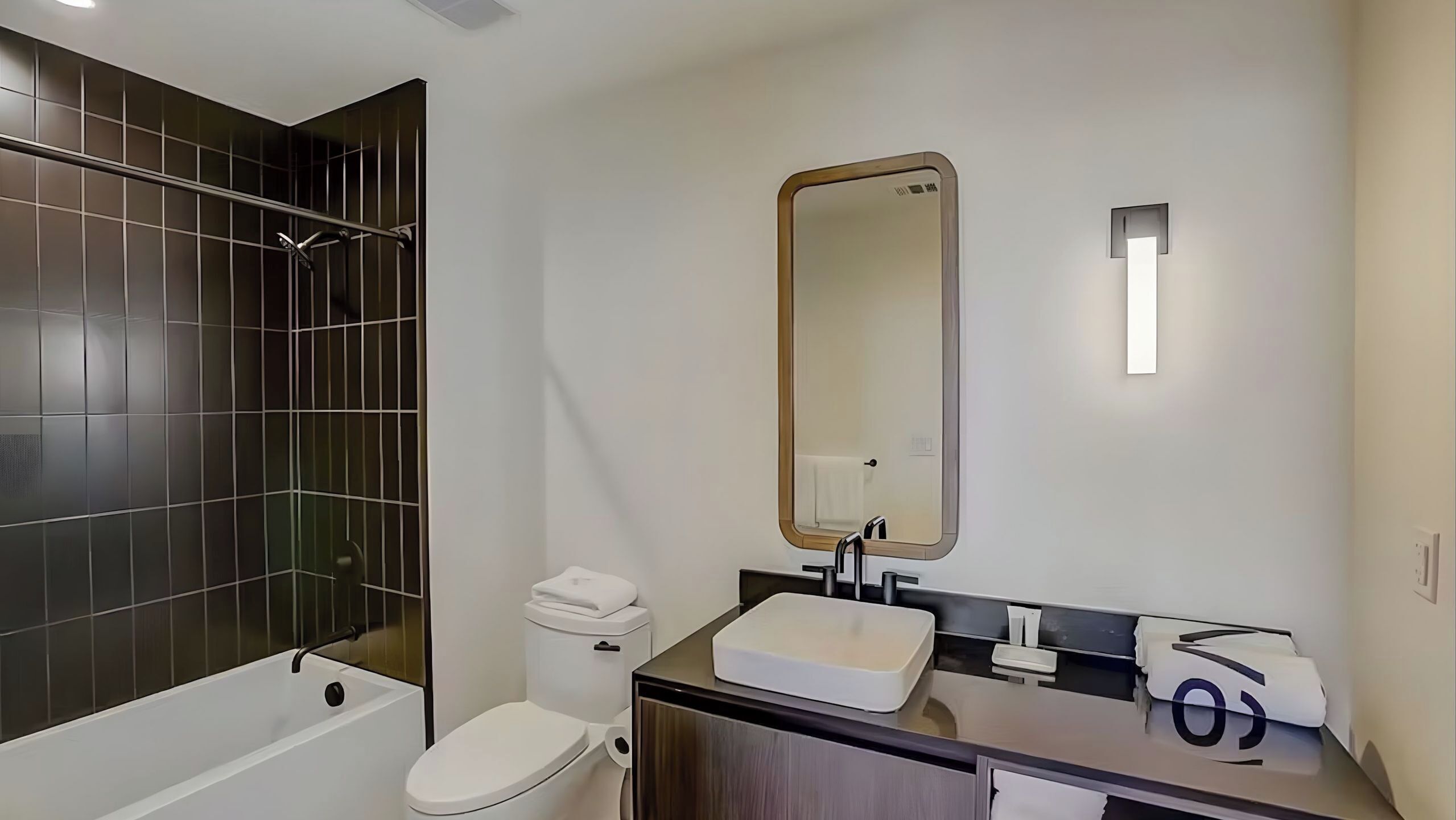 Une salle de bain moderne avec une baignoire, des toilettes, un lavabo et un grand miroir.