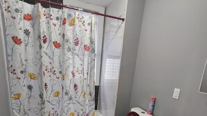 A bathroom with a toilet, sink, and shower curtain with floral patterns.