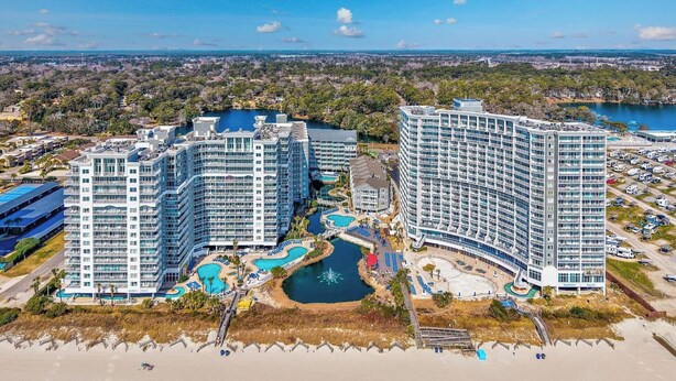 A resort with multiple high-rise buildings, a central pool area, and a beach.