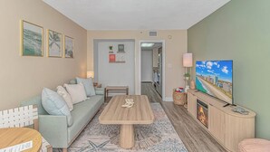 A living room with a sofa, coffee table, fireplace, TV, and framed pictures on the wall.