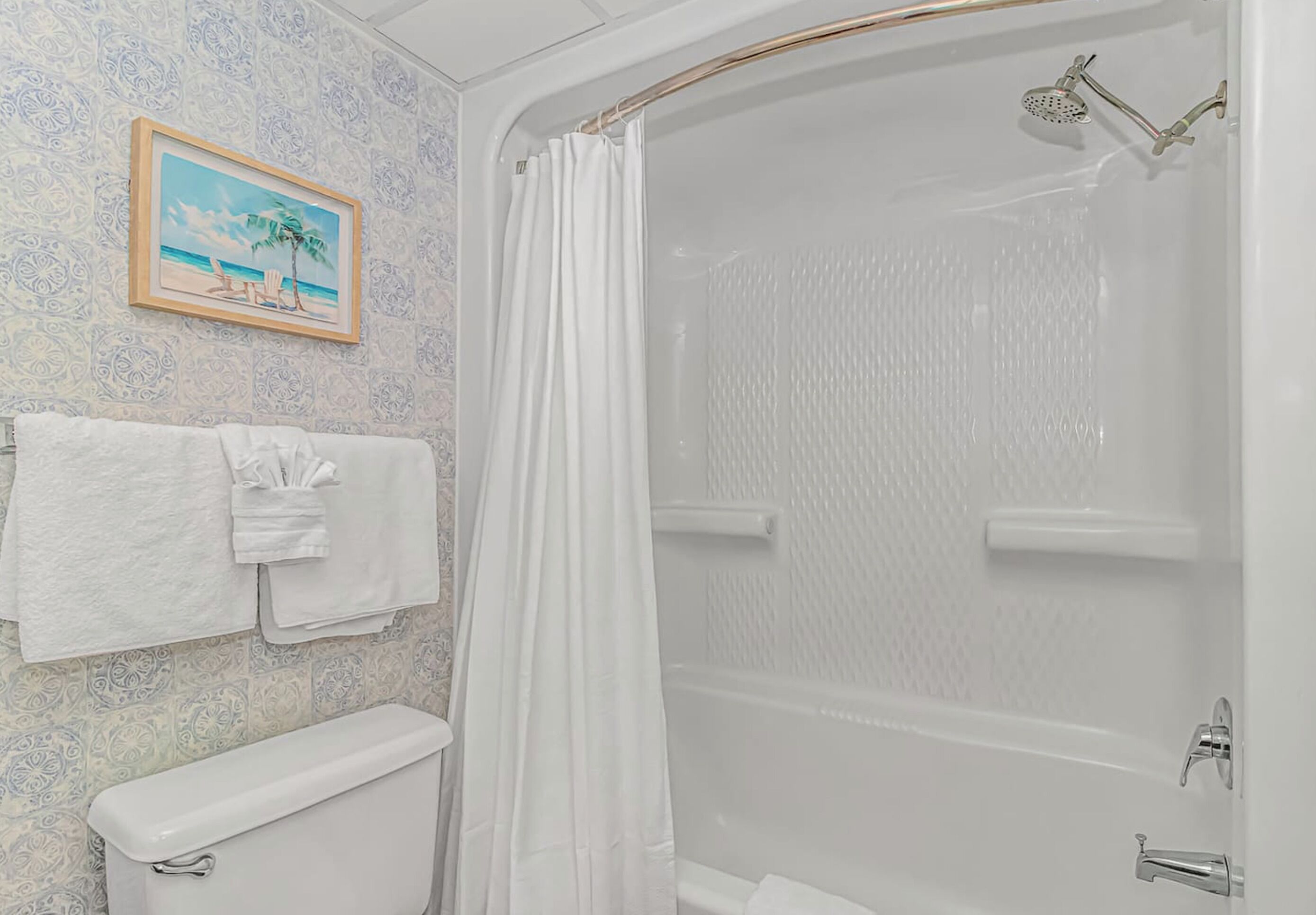 A bathroom with a toilet, a shower with a glass door, and a towel rack with towels.