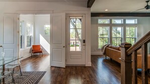 Una habitación amplia con pisos de madera, una mesa de vidrio, un sofá de cuero y una escalera con barandilla de madera.