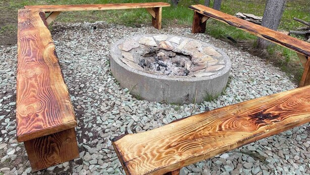 A fire pit surrounded by wooden benches in a natural setting.