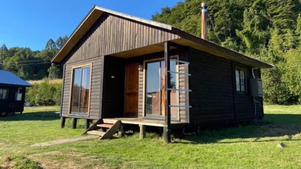 A small wooden cabin with a sloped roof, a front porch, and a chimney. - cabañas nuevo amanecer paillaco valdivia (Paillaco)