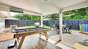 A pool table in a covered outdoor area with a wooden deck, chairs, and a designated smoking area sign. - Breezy Lutz Home w/ Patio: Perfect for Long Stays (Lutz)
