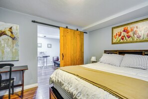 Um quarto com uma cama, uma porta de madeira, um quadro de tulipas e uma cadeira.