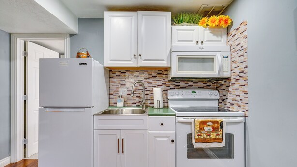 A compact kitchen with white cabinets, a microwave, and an oven. - 12 Mi to Temple Square: Cozy + Convenient Apt! (Taylorsville)
