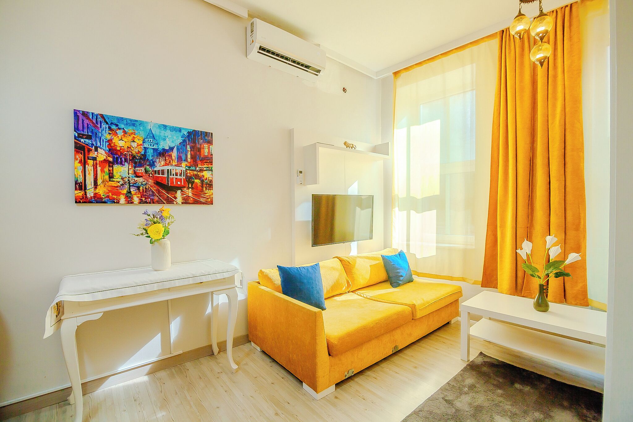 Un salón moderno con un sofá amarillo, una consola blanca y un cuadro colorido en la pared.