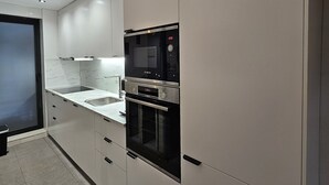Une cuisine moderne avec des meubles blancs, un four encastré et un four à micro-ondes.