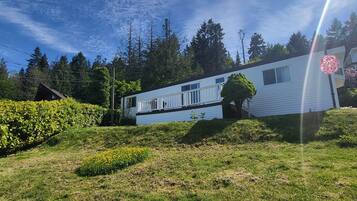 Uma casa térrea com fachada branca, rodeada por um jardim bem cuidado e um cenário de mata.