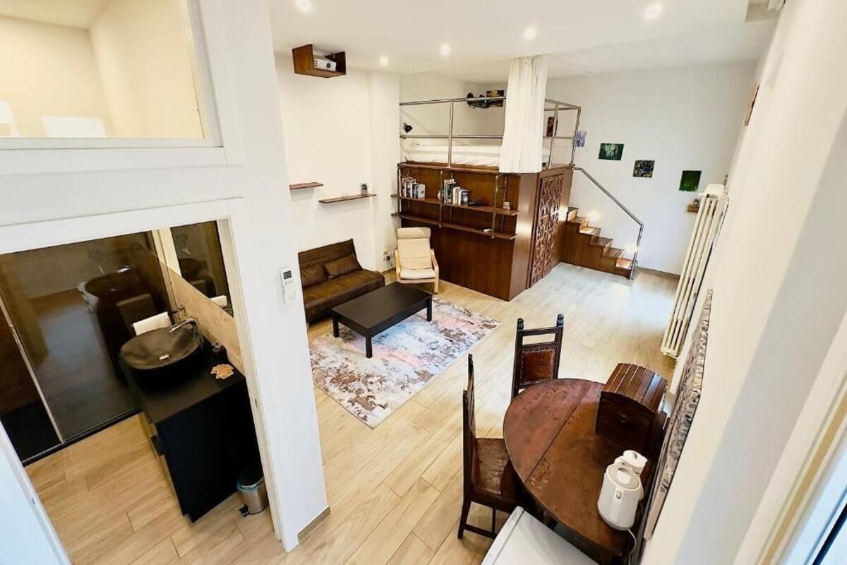 A modern apartment with a dining area, kitchen, and a loft bedroom with a balcony.