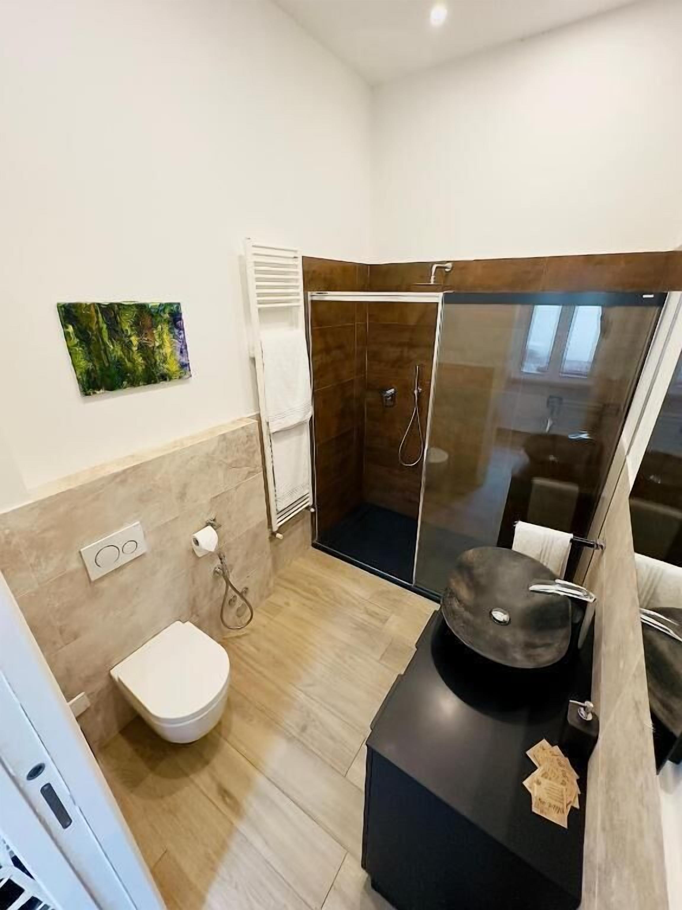A modern bathroom with a shower, toilet, and a black vanity with a mirror.