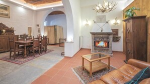 Ein gemütliches Wohnzimmer mit Kamin, Ledersofa, Essbereich und einer Kristallleuchtre.