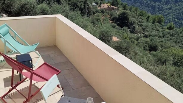 Un balcone con tavolo e sedie, affacciato su un paesaggio montuoso.
