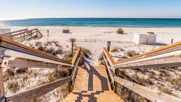 Un paseo marítimo de madera que conduce a una playa con vista despejada al océano.
