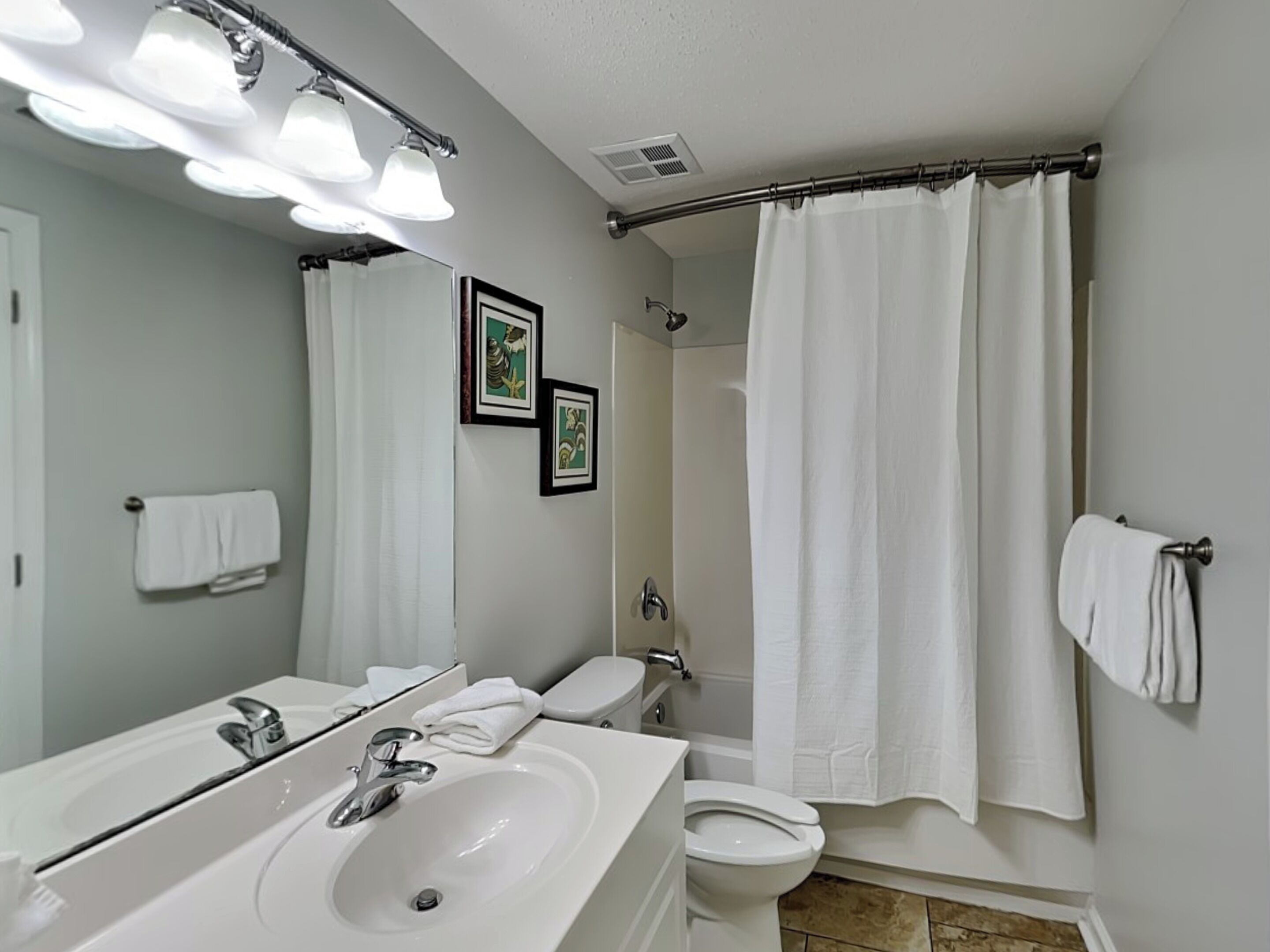 A bathroom with a sink, mirror, toilet, and shower curtain.