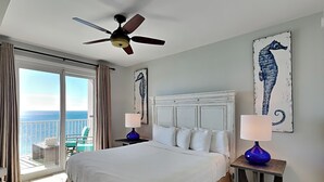 Ein Hotelzimmer mit einem großen Bett, zwei Nachttischen, einem Deckenventilator und Bildern an den Wänden.