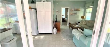 A spacious living area with a sofa, a dining table, and a kitchen area with cabinets and a refrigerator.