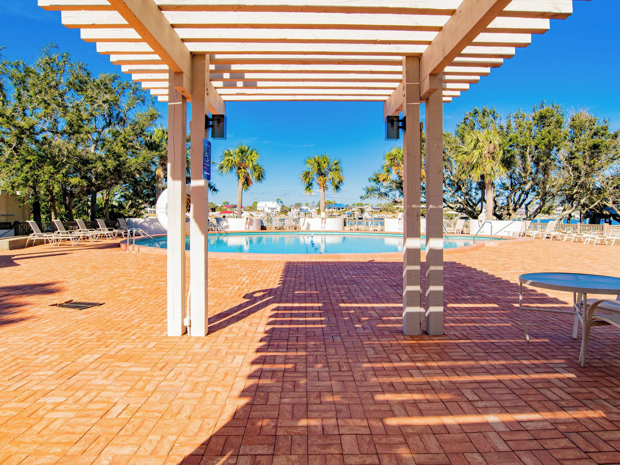 A pool area with a pergola, lounge chairs, and a clear view of the pool.