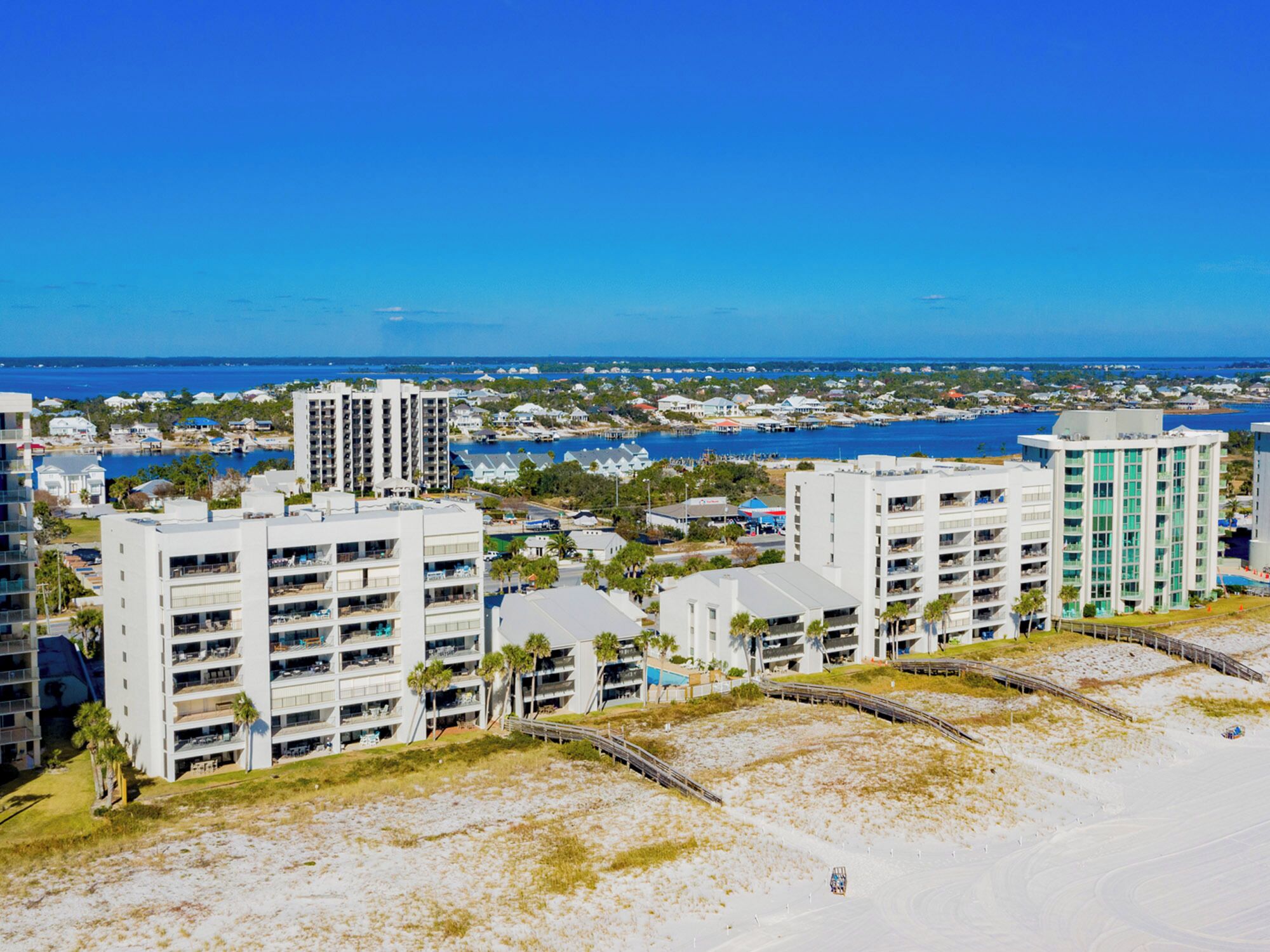 A coastal hotel with multiple floors, a beach view, and a marina in the background.