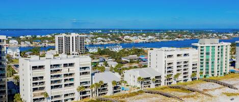 A coastal hotel with multiple floors, a beach view, and a marina in the background.