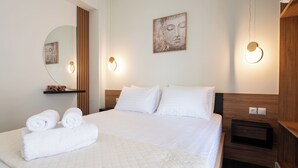 A neatly made bed with white linens, a round mirror, and a wall-mounted artwork. - Modern Rooms Exarchia Room 2 (Athina)