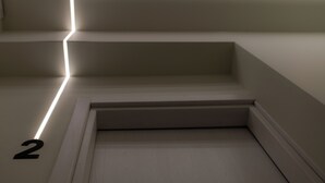 A modern staircase with a minimalist design, featuring a continuous light strip along the edge. - Modern Rooms Exarchia Room 2 (Athina)