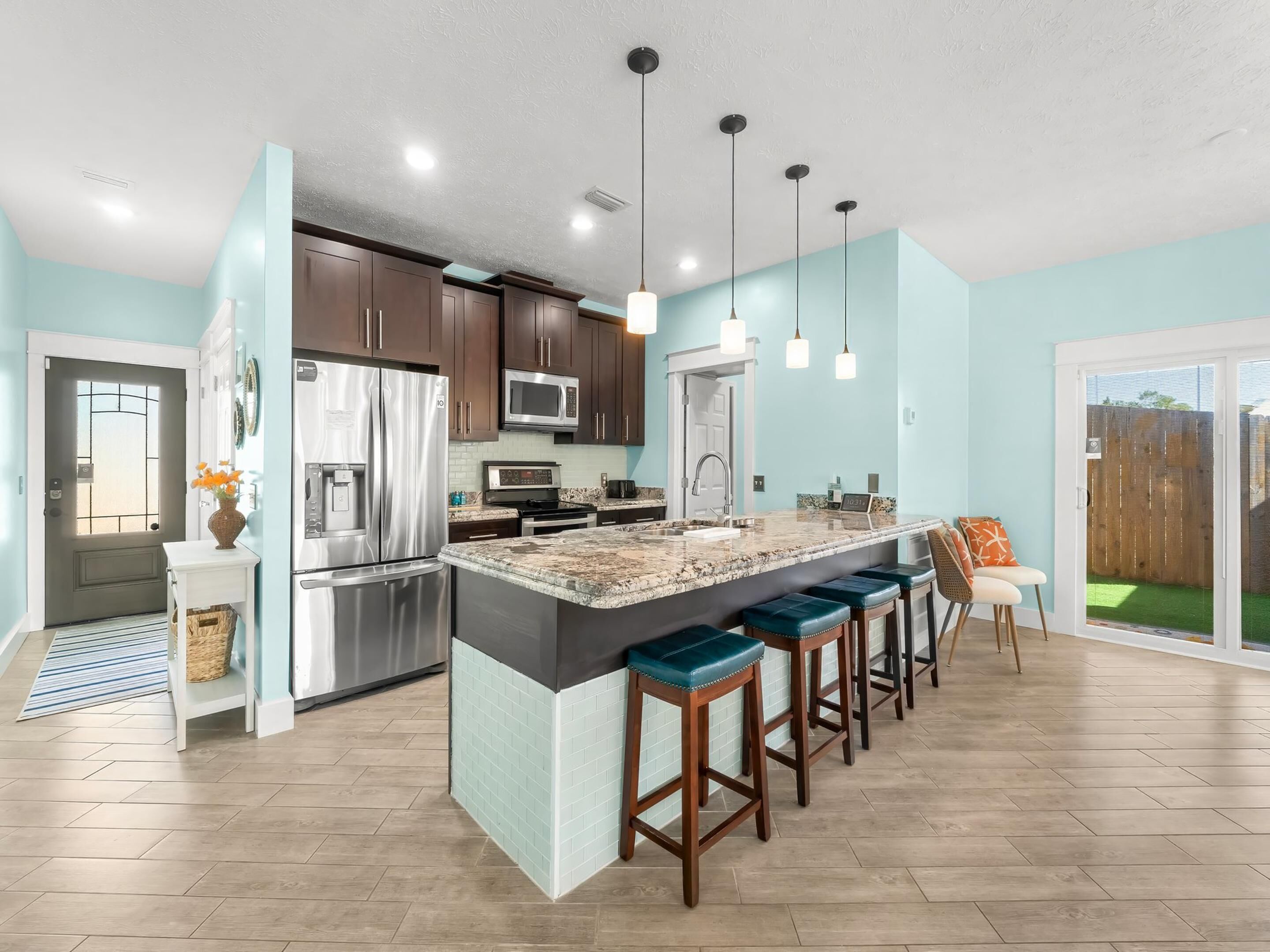 A modern kitchen with a central island, stainless steel appliances, and pendant lighting.