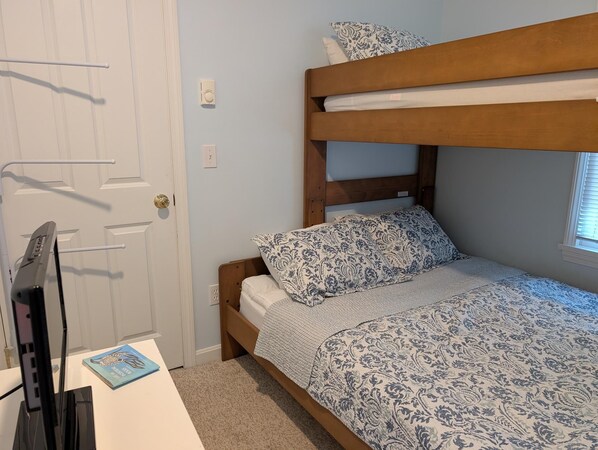 A bunk bed with patterned bedding, a desk with a book, and a door with a handle. - Fully furnished cottage, minutes from the beach. (Wells)
