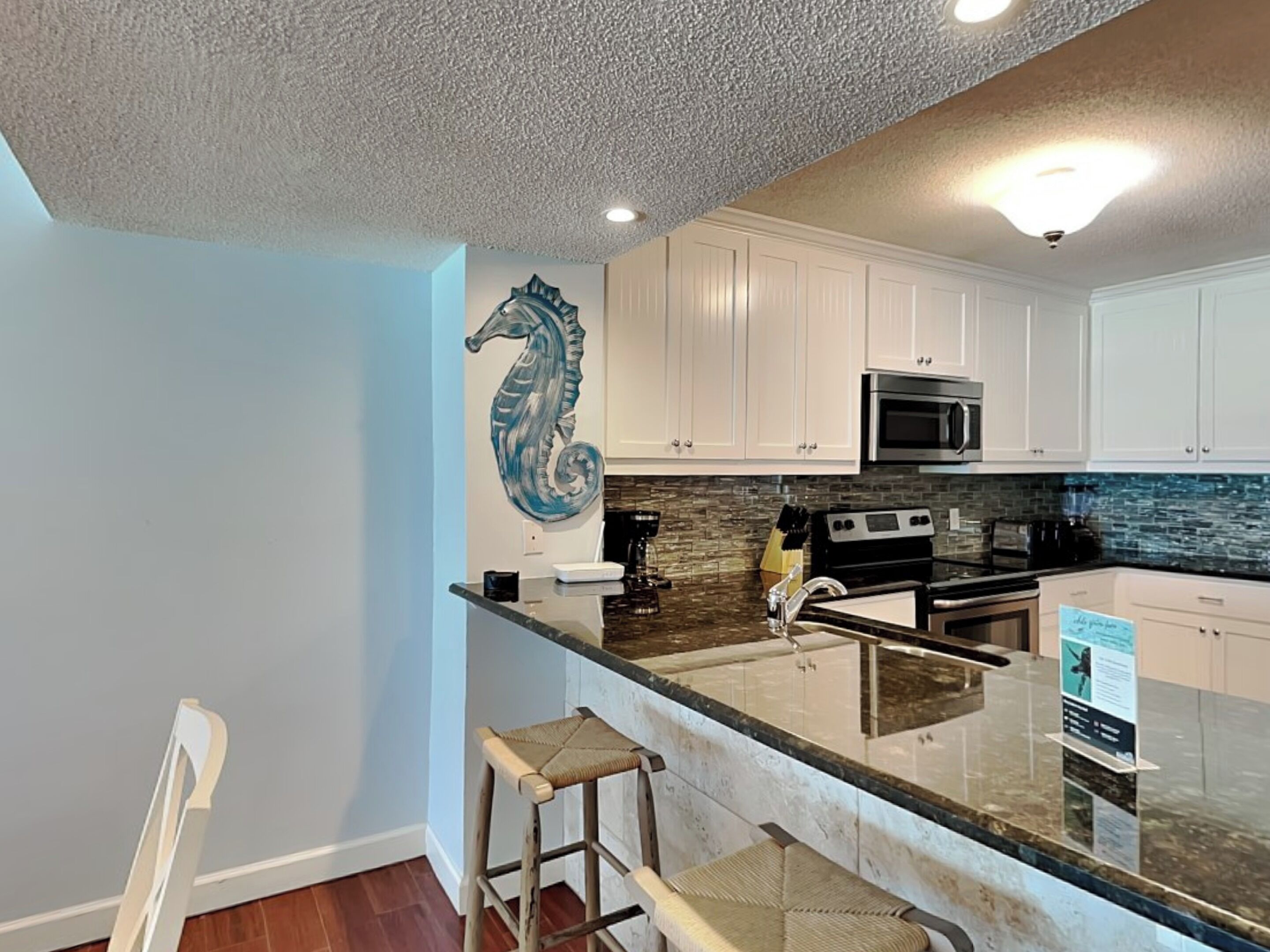A modern kitchen with white cabinets, a stainless steel oven, and a backsplash.