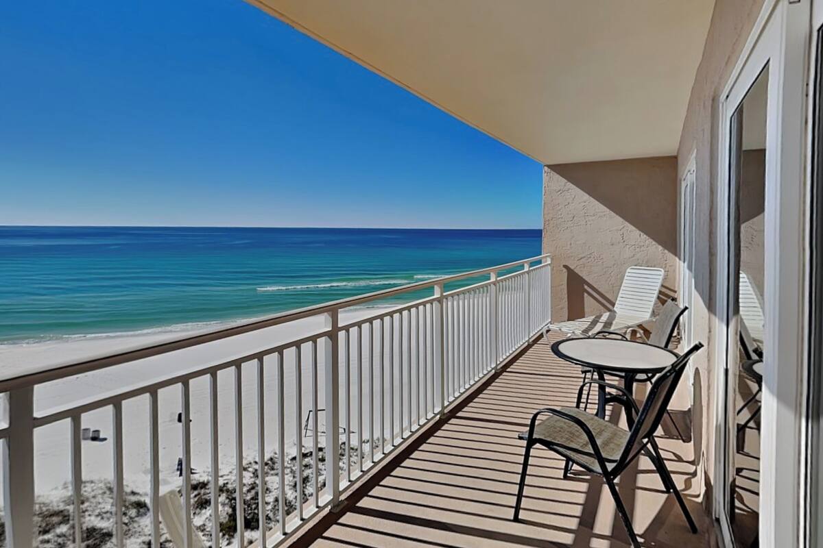 Varanda com vista para o oceano, mesa com cadeiras e guarda-corrimão.