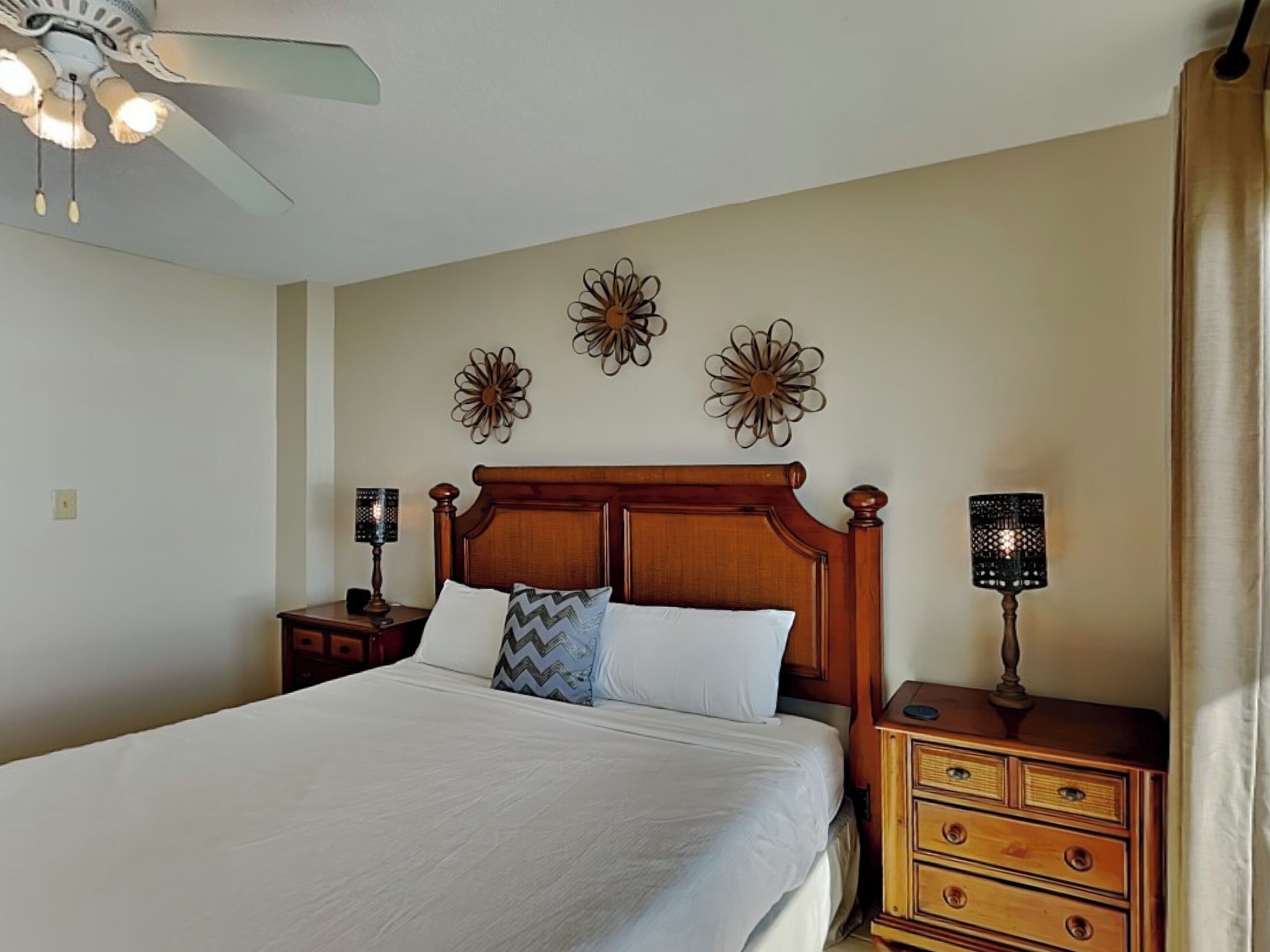 Una cama bien hecha con cabecera de madera, dos mesitas de noche con lámparas y decoración en la pared.