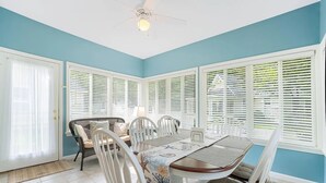 A dining area with a table and chairs, a ceiling fan, and large windows with blinds. - Cottages at Summer Village, fully furnished cottage, Wi-fi, heated pools, hot tub (Wells)
