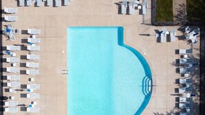 An aerial view of a swimming pool with lounge chairs and umbrellas arranged around it. - Cottages at Summer Village, fully furnished cottage, Wi-fi, heated pools, hot tub (Wells)