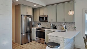 Una cocina moderna con electrodomésticos de acero inoxidable, un salpicadero tipo espiga y suelo de madera.